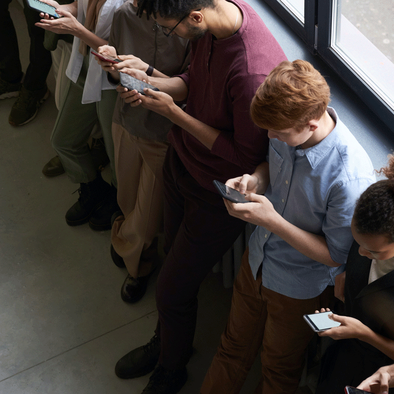 People in a queue looking at their cell phones.