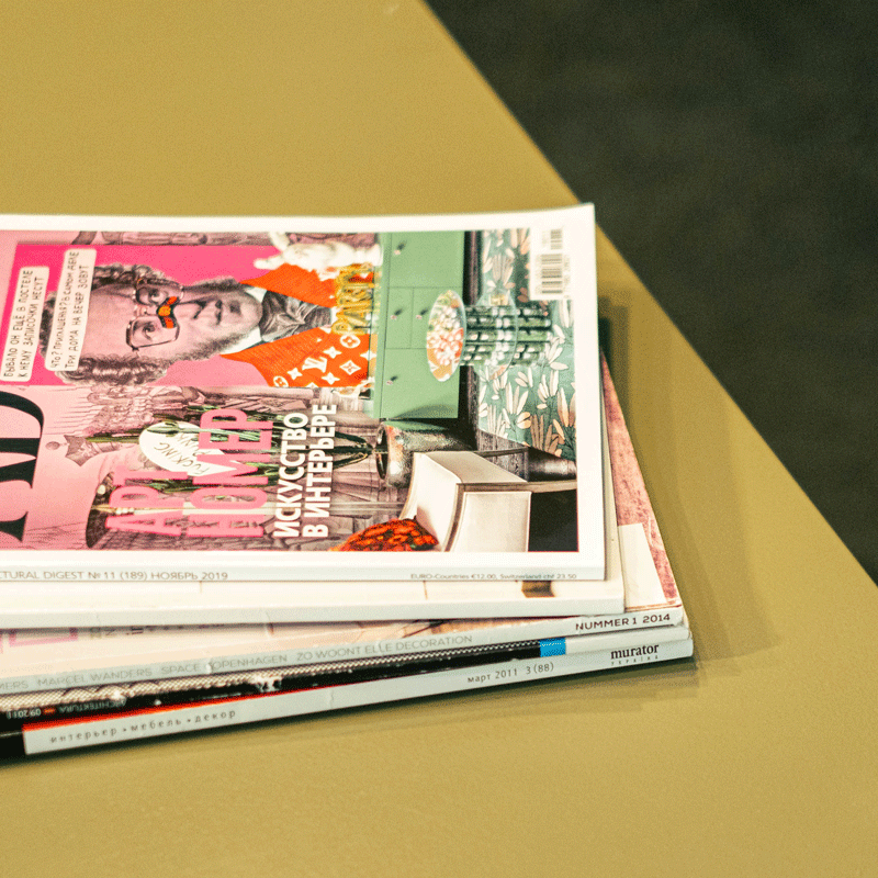 Glossy magazines stacked 5 high on a table.